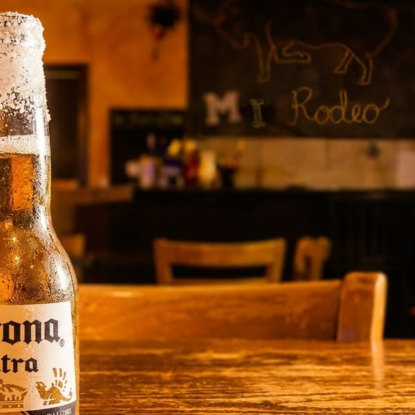 Salt-rimmed Corona Extra beer bottle on a wooden table in a restaurant with a Christmas tree.