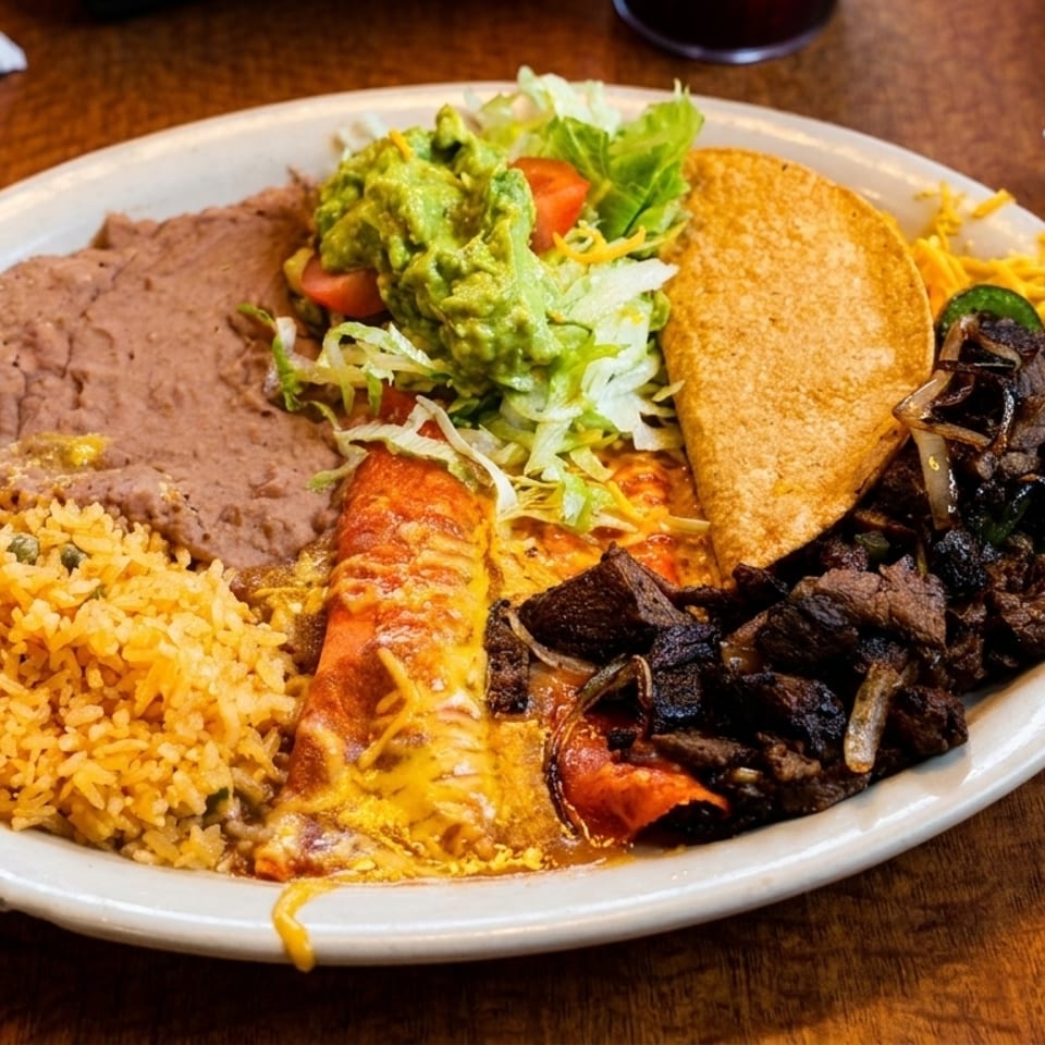 A large plate of Mexican food with rice, beans, enchilada, taco, guacamole, and fajita meat.